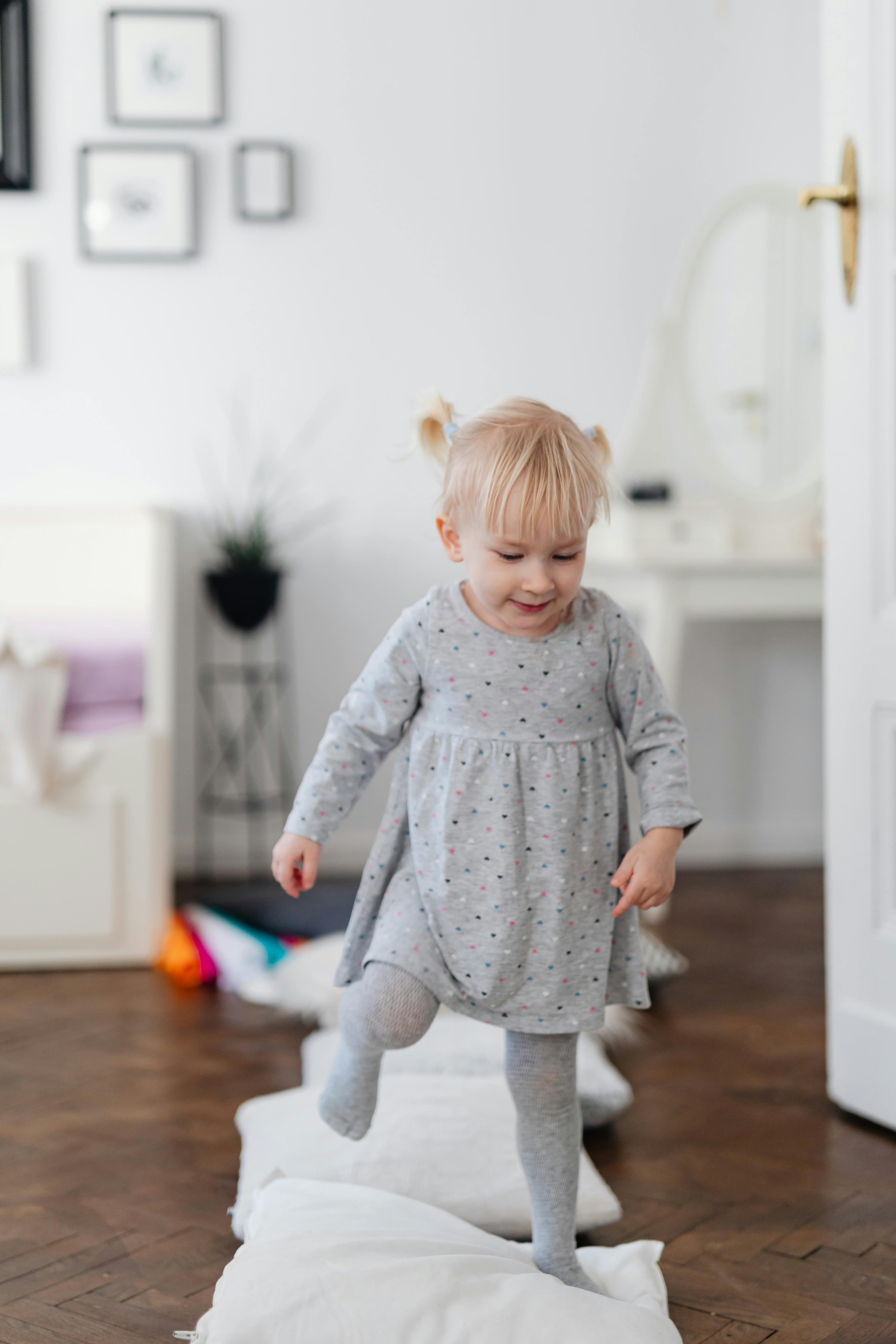 Toddler stepping over couch cushions on the floor