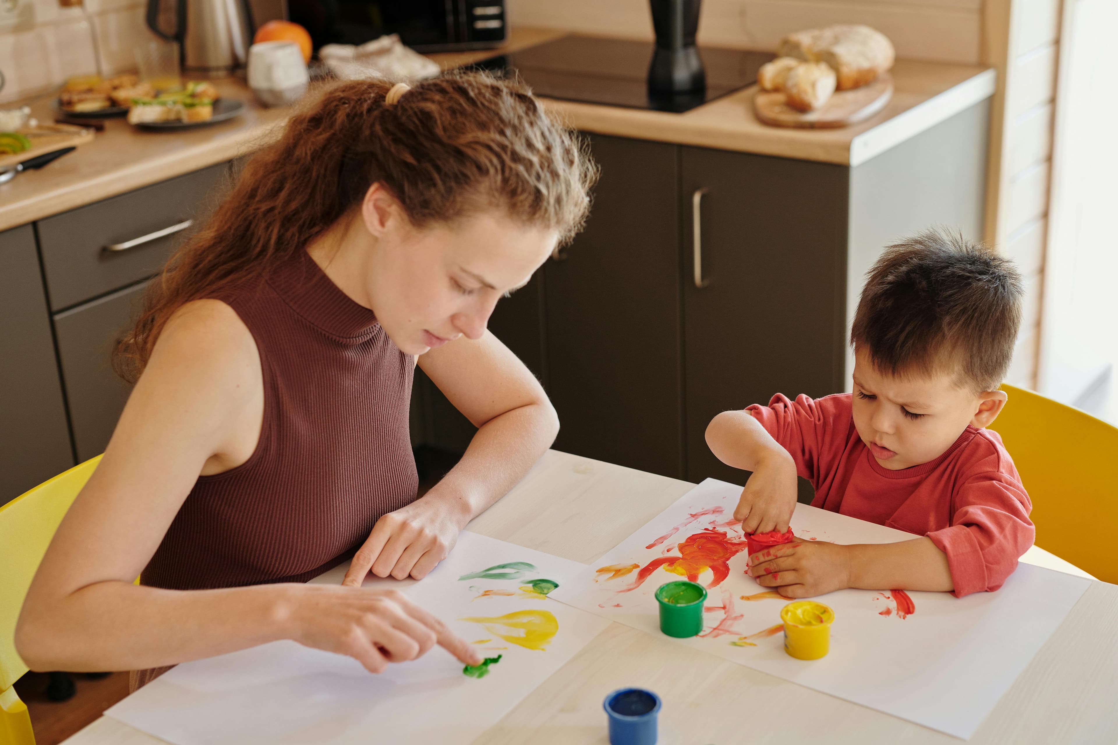 Parent and child painting side by side at a kitchen table