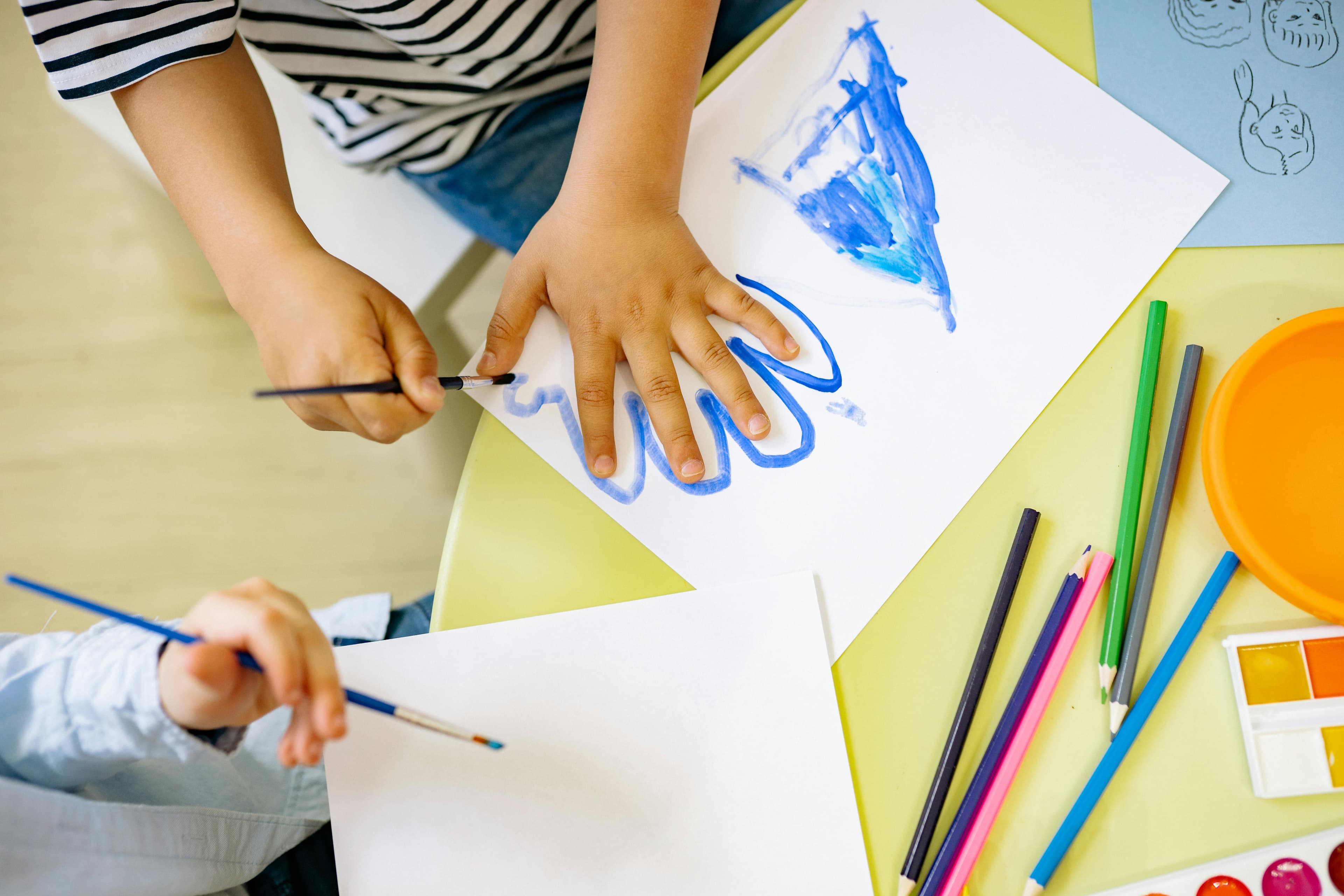 Child's hand making paint marks on paper at the art table