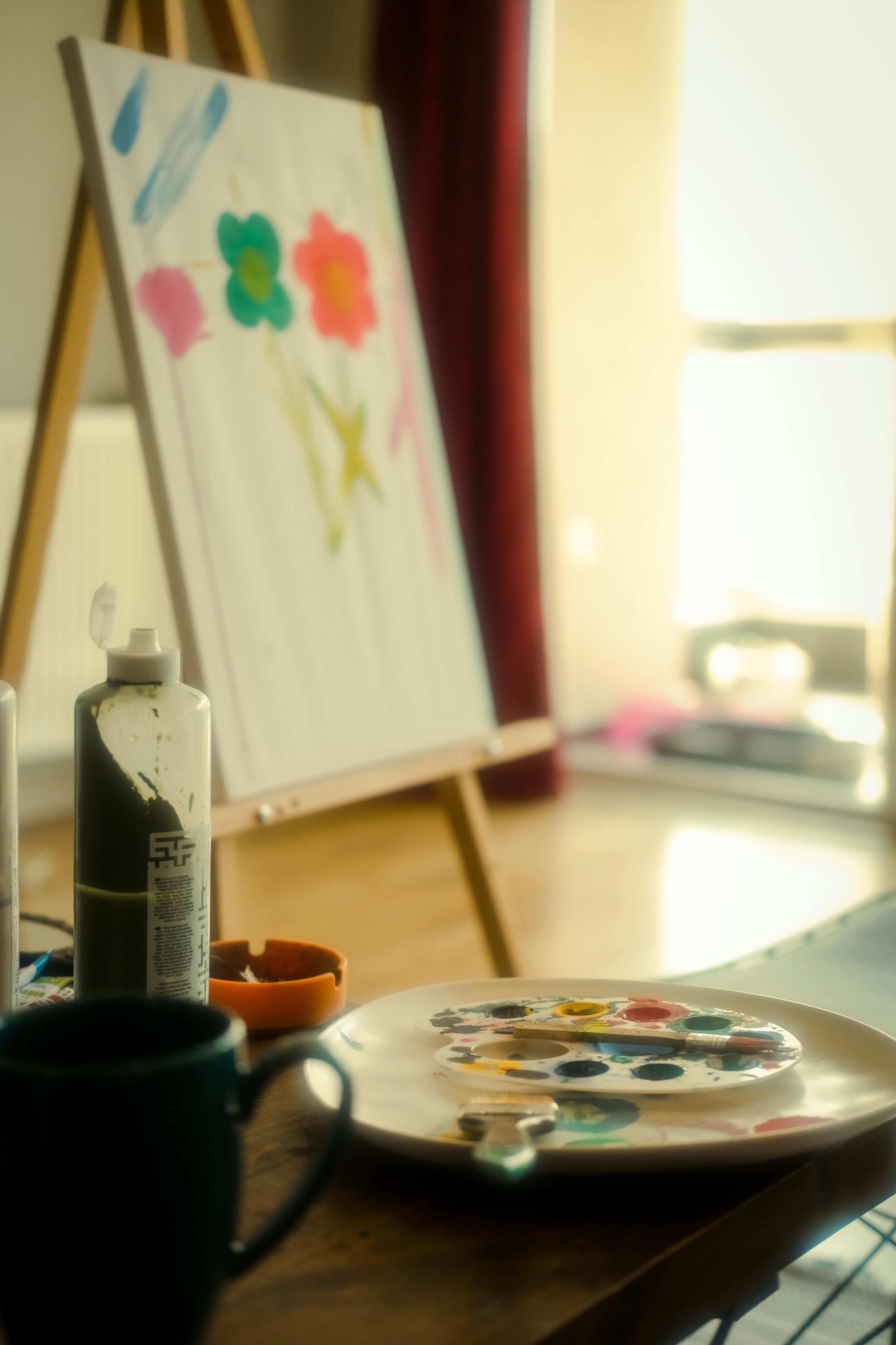 Home art corner with easel, canvas, and paint supplies in warm natural light