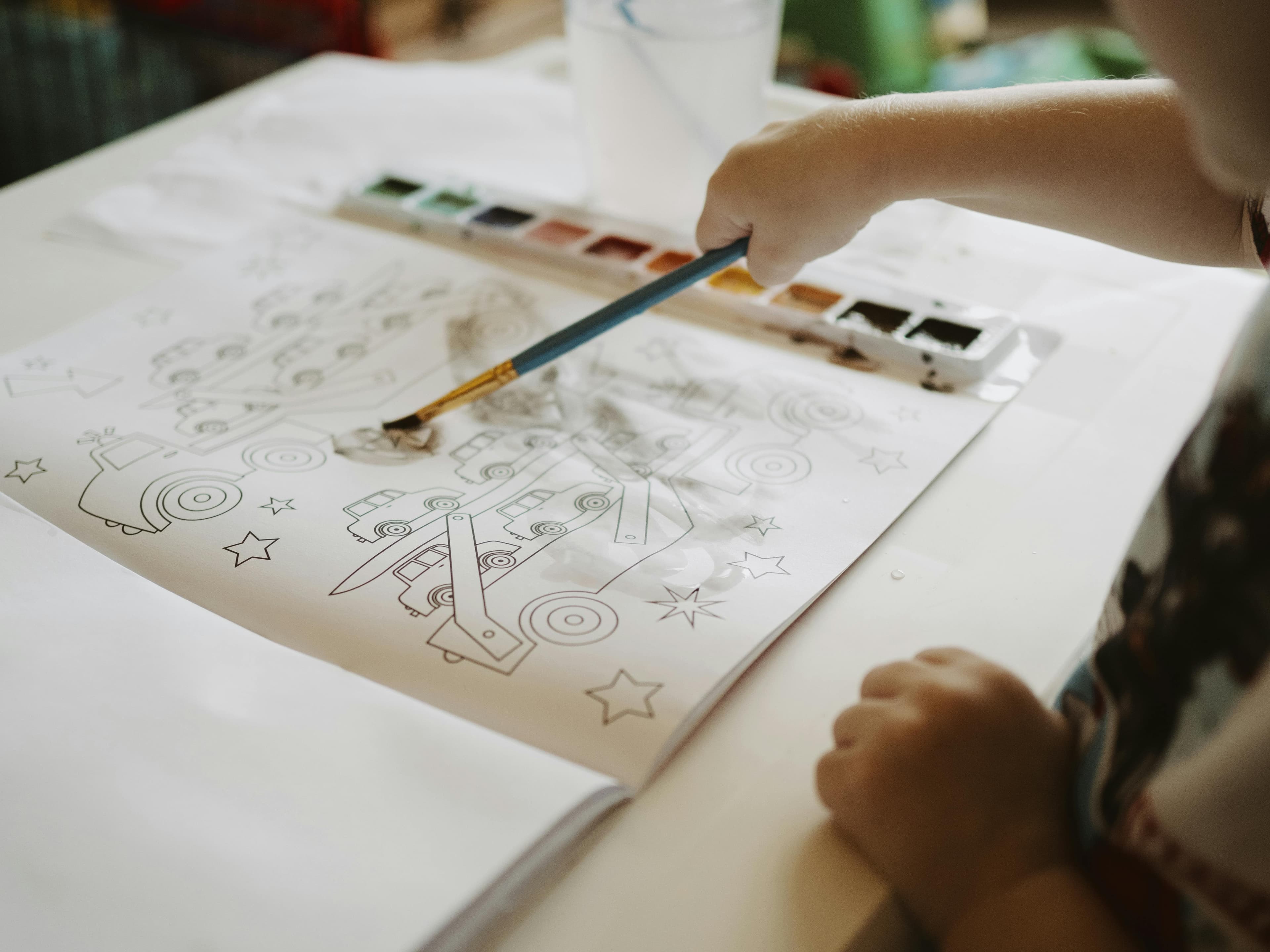 Child using a brush on a water painting book page